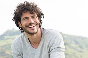 Man smiling outside in grey sweater
